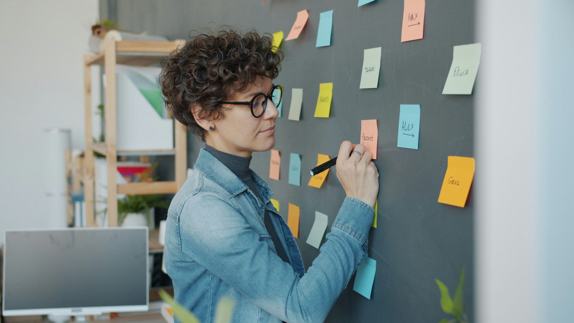Woman writing on sticky notes on a wall.